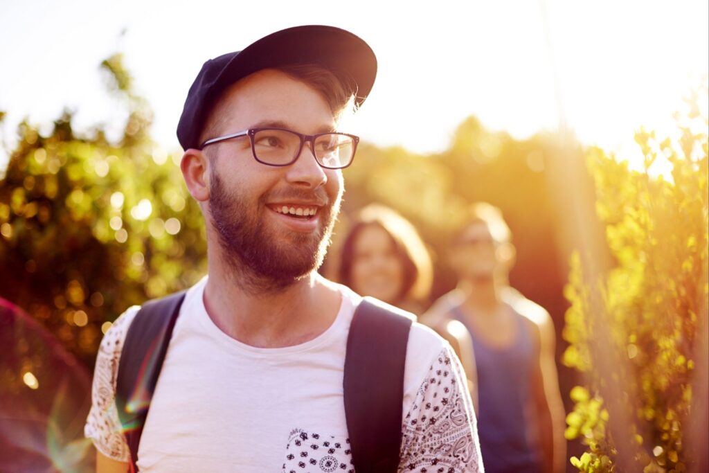 Smiling man walking outdoors in sunlight, symbolizing spiritual clarity, peace, and confidence as a spiritually sensitive person