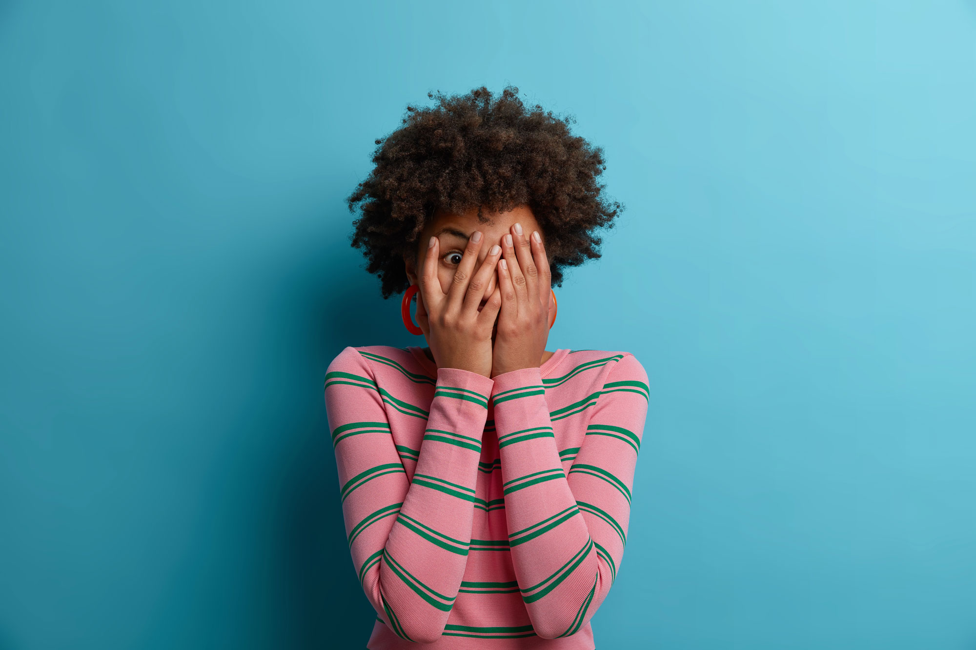 Woman covering face in embarrassment, representing fear of looking foolish and overcoming insecurity through faith