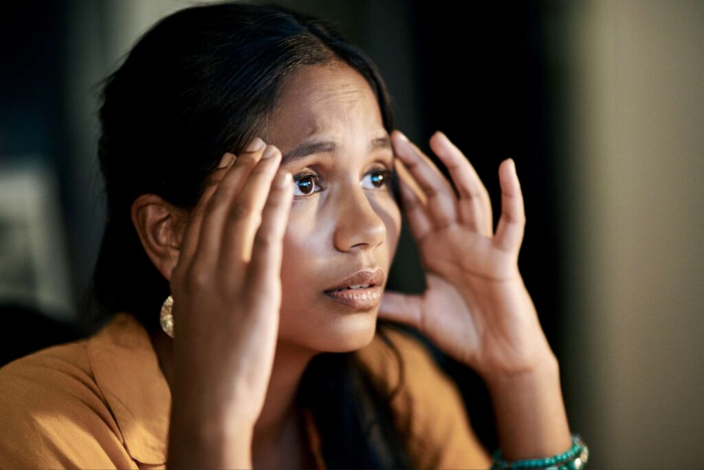 Woman holding her temples while processing new understanding during a season of holy deconstruction