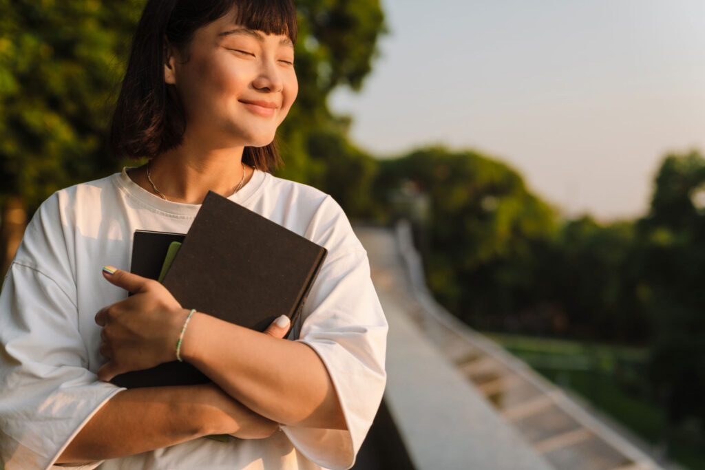 woman reflecting on wisdom and understanding while holding books outdoors