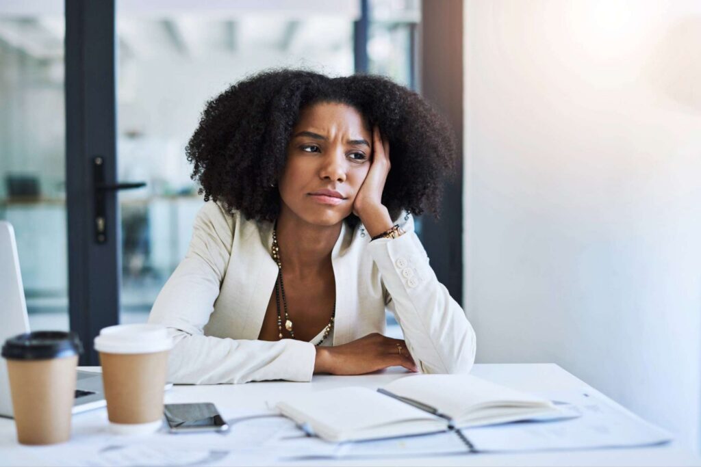 Woman seated at office desk in quiet reflection, appearing inwardly unsettled during a season of emotional and spiritual processing