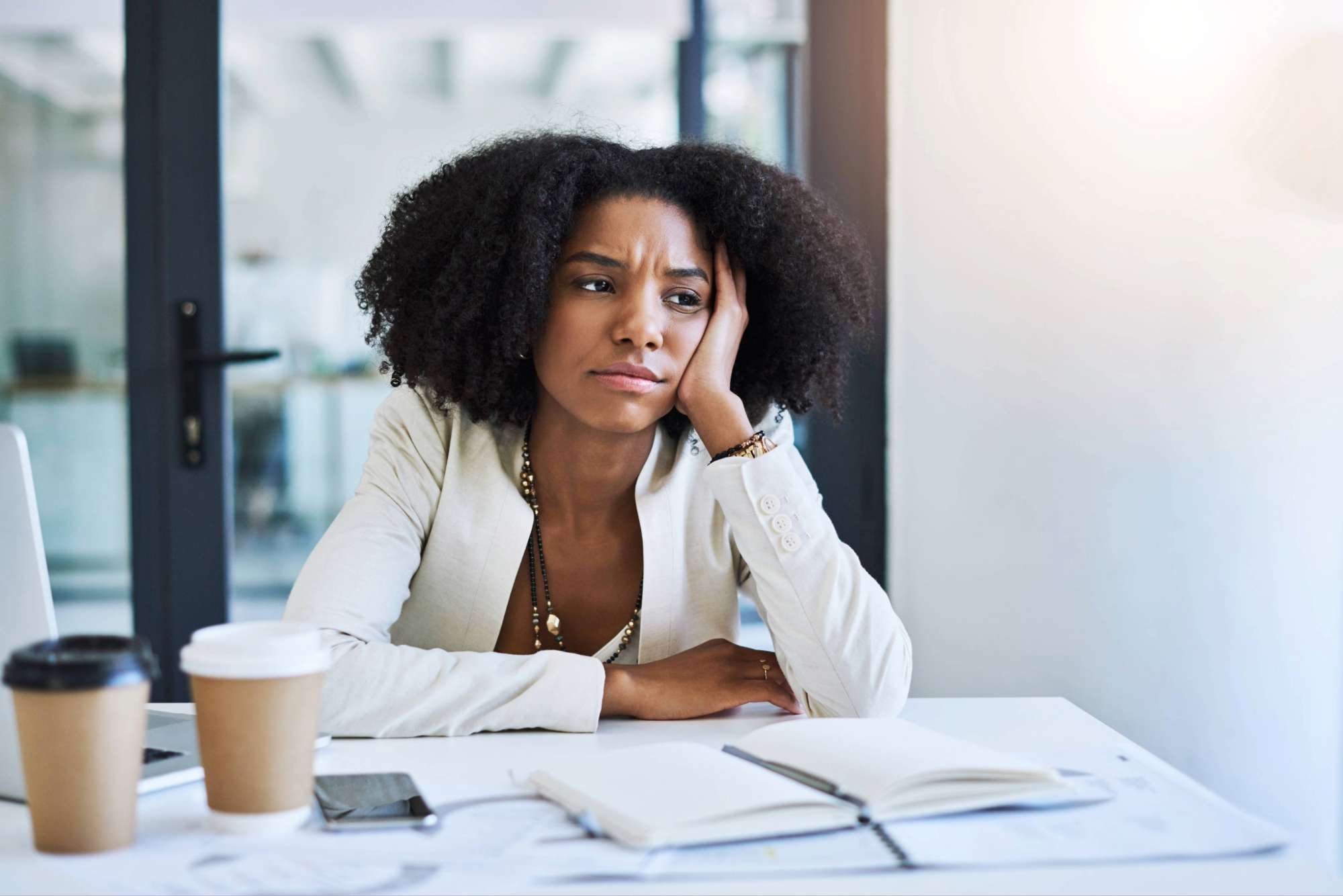 Woman seated at office desk in quiet reflection, appearing inwardly unsettled during a season of emotional and spiritual processing