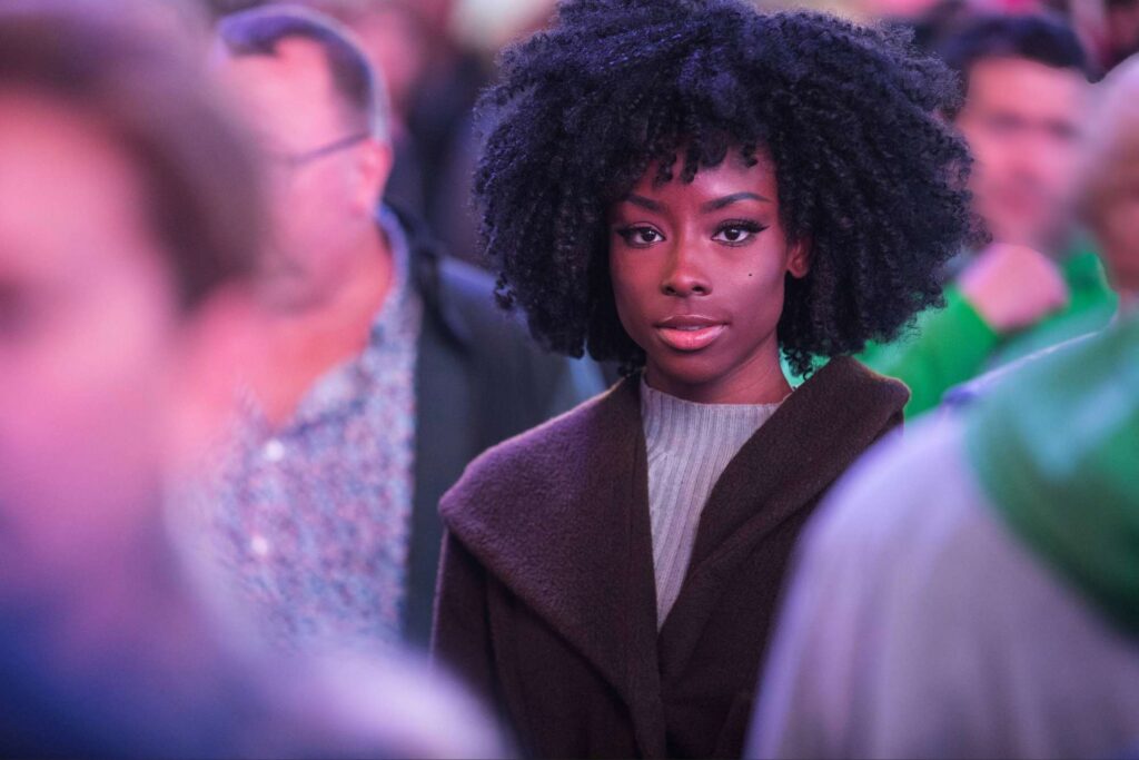Woman standing calmly in a crowded environment, remaining grounded and at peace despite the surrounding atmosphere