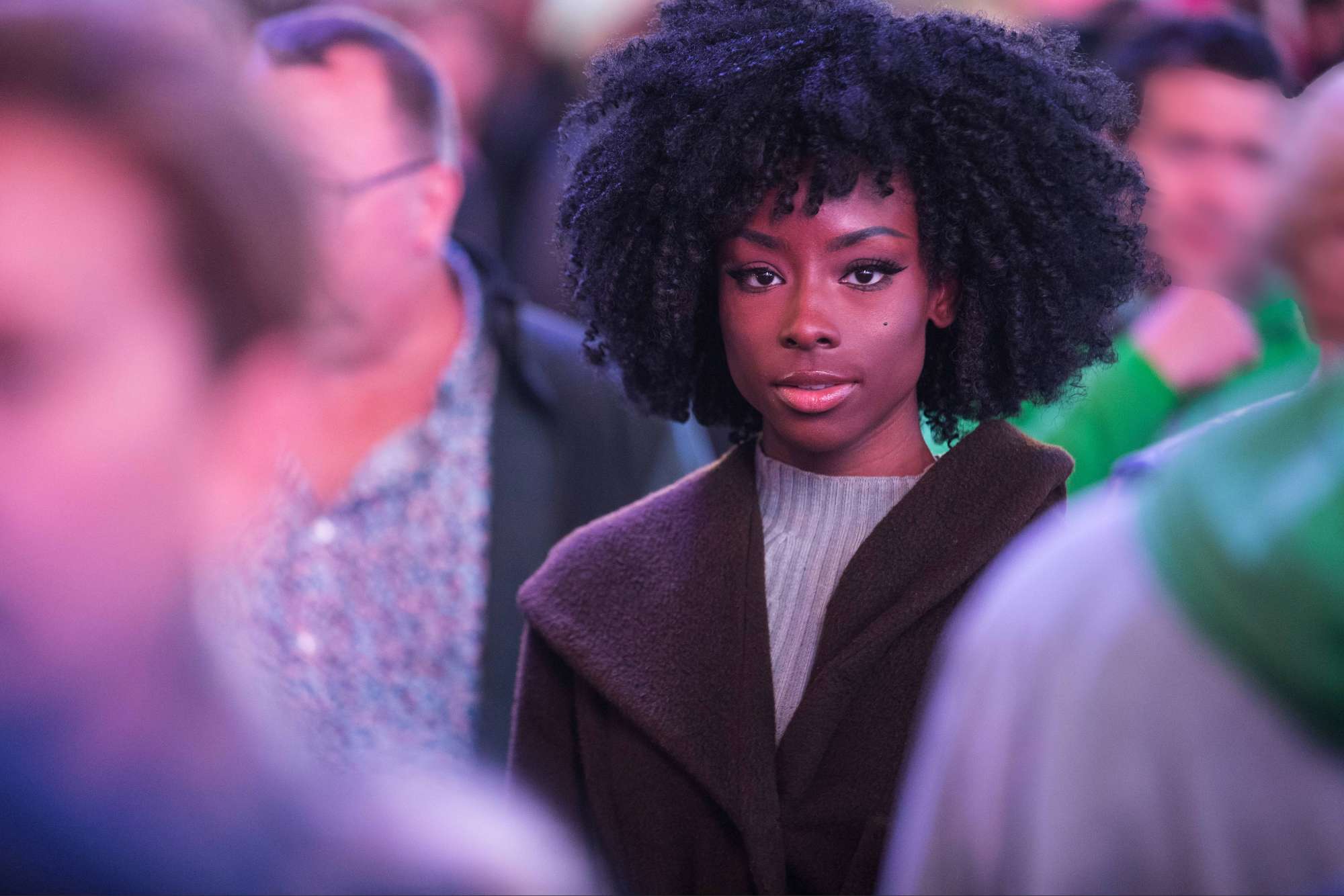 Woman standing calmly in a crowded environment, remaining grounded and at peace despite the surrounding atmosphere