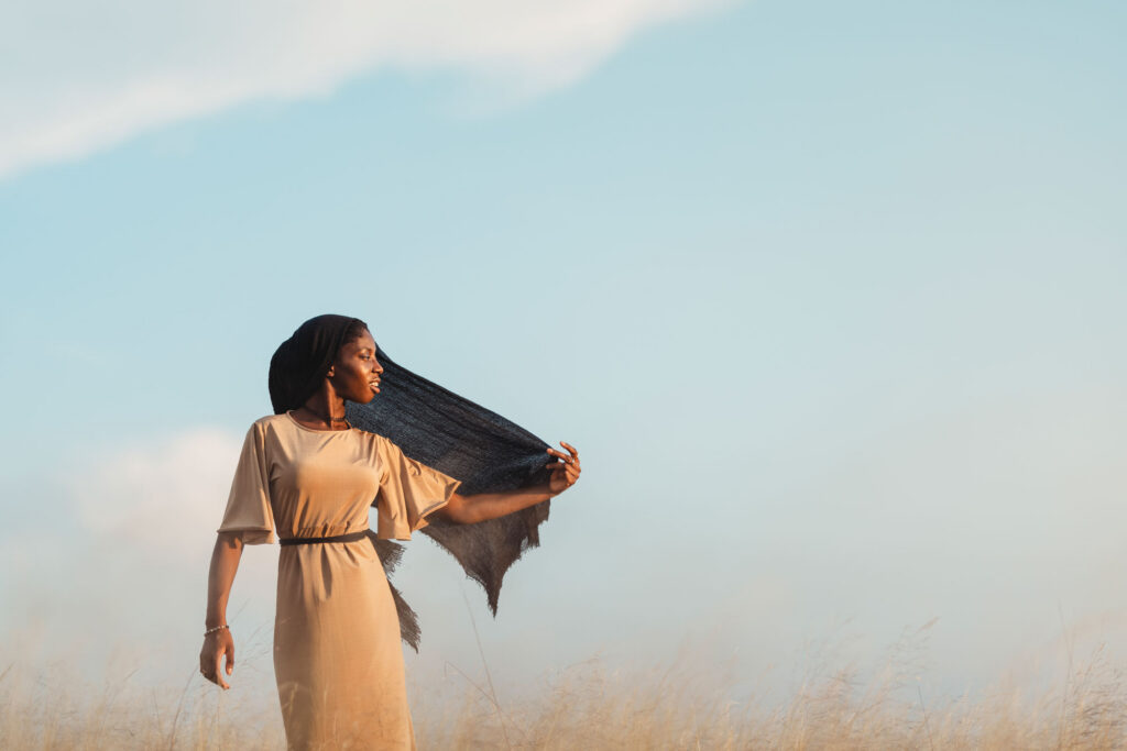 Woman standing in open air with a light covering flowing around her, symbolizing God’s peace and protection without striving