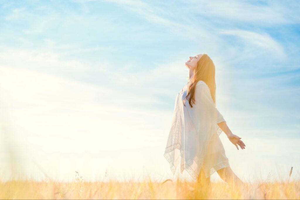 Woman standing freely in golden light, representing Kingdom identity in Christ through freedom, surrender, and Heaven’s true order