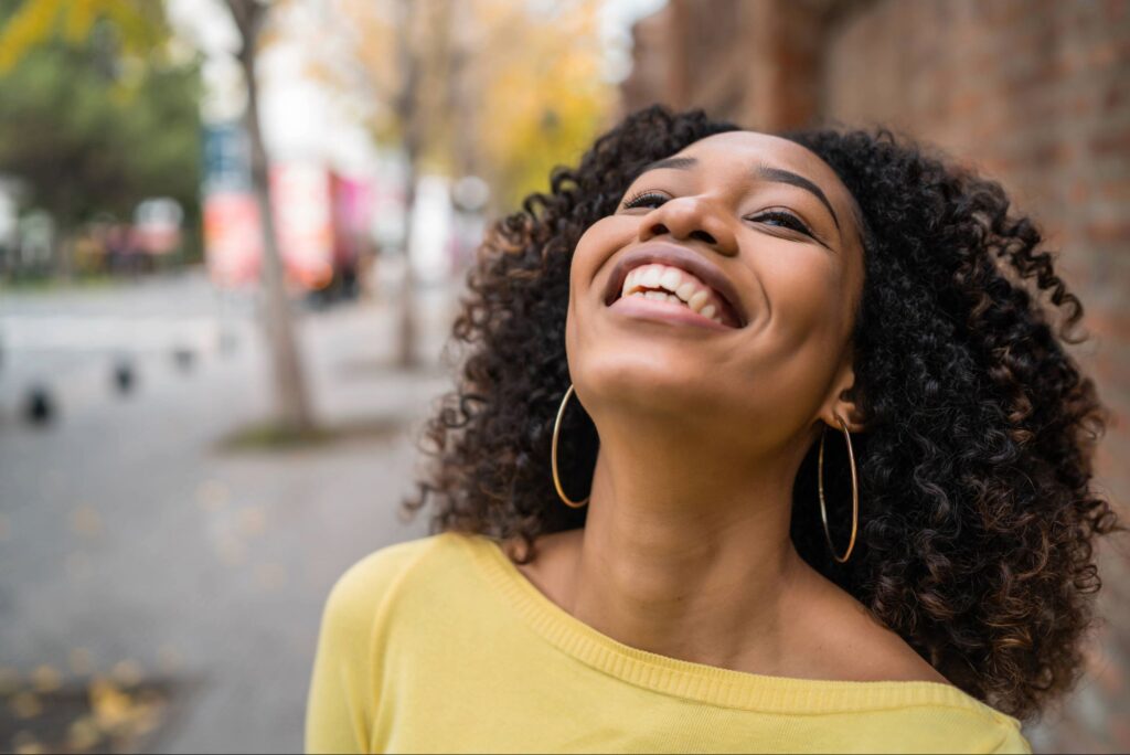 Woman smiling upward with joy and freedom, representing rekindling your passion for God through renewed intimacy and relationship