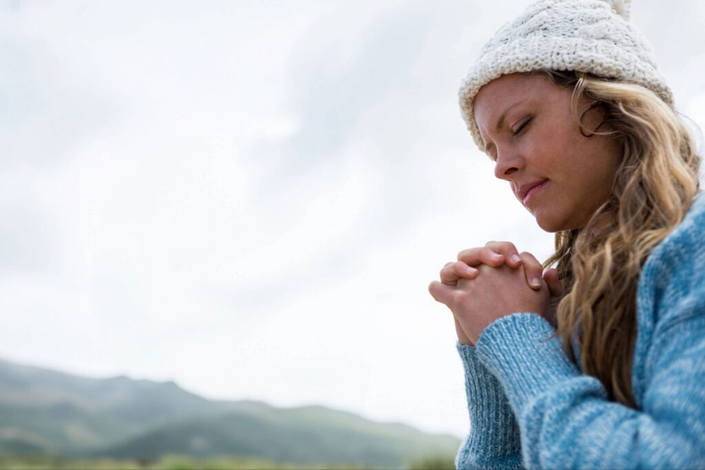 Woman in quiet prayer outdoors, reflecting surrender and rekindling your passion for God through deeper nearness to His presence